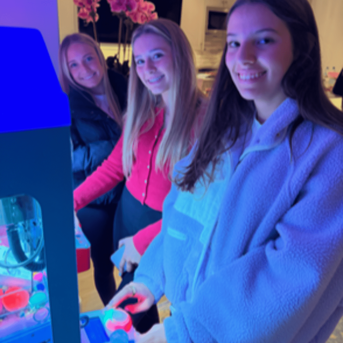 Teens enjoying a claw machine rental at a party in Highland Park Texas.
