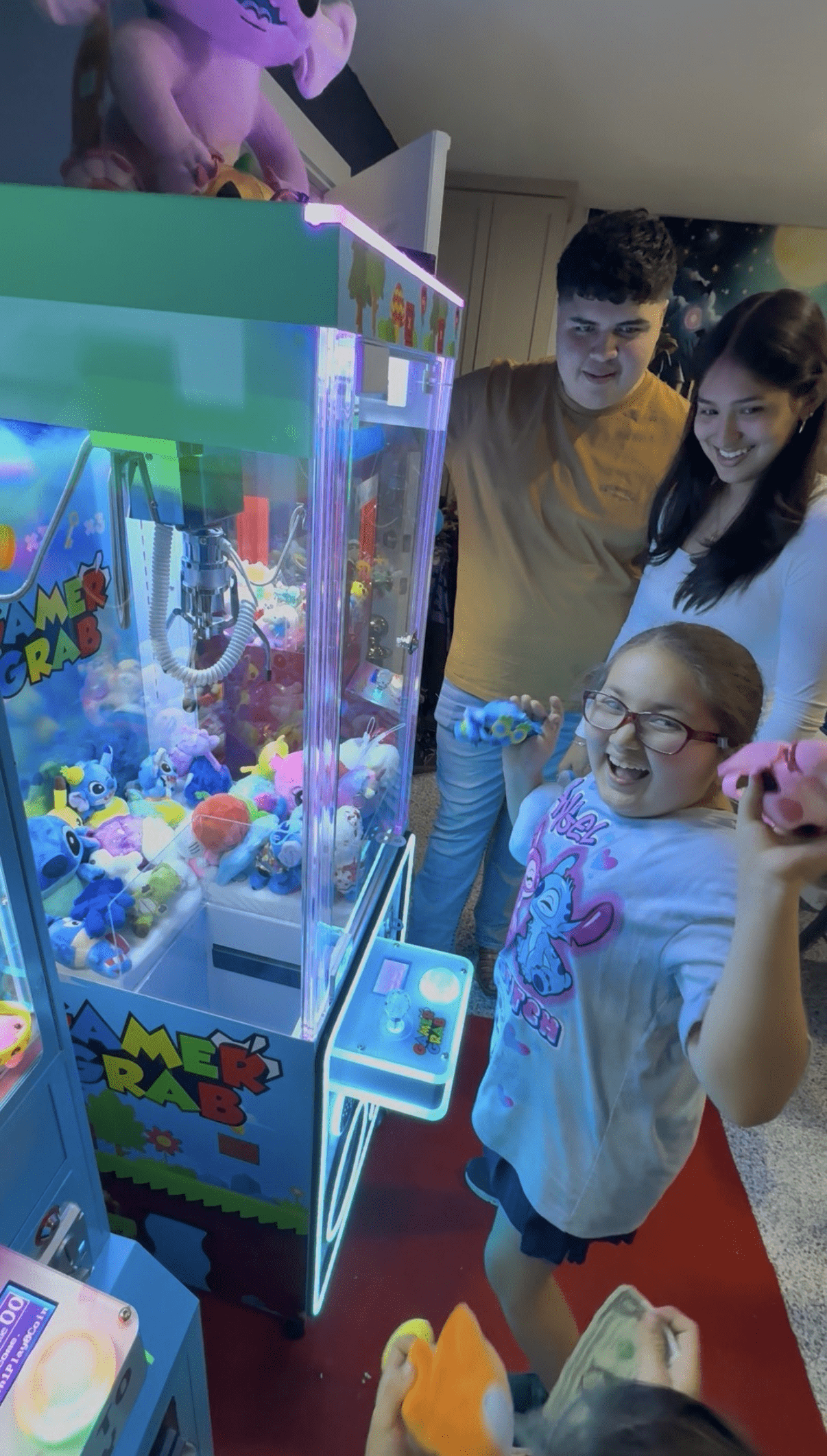 Kids smiling while playing a claw machine at a birthday party in Melissa, Texas, enjoying prizes from a Chuck Vending claw machine rental.