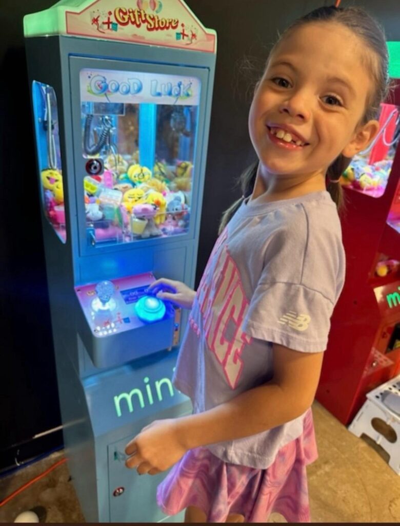 Smiling girl playing a claw machine at her birthday party in Denton Texas.