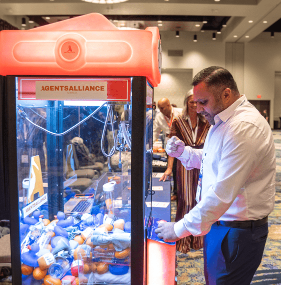 Trade show attendee playing a claw machine at a booth to attract visitors and increase engagement.